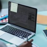 crop multiethnic students with laptop studying at table